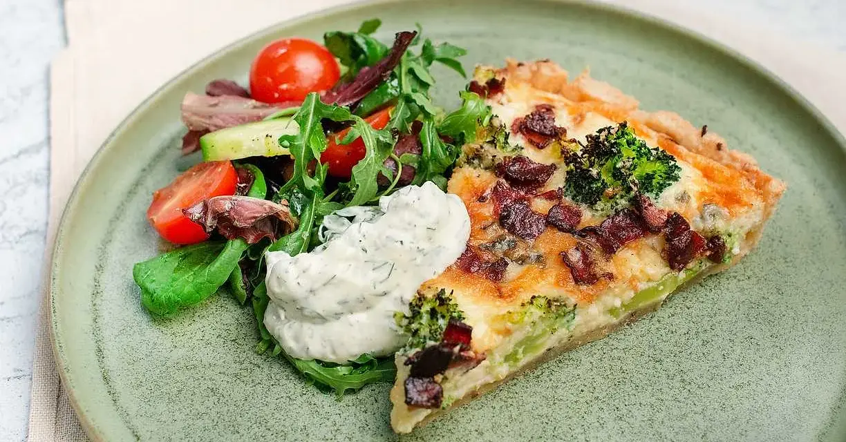 En bit ost och broccolipaj med knaperstekt bacon, serverad med en fräsch sallad och en klick vitlökssås.