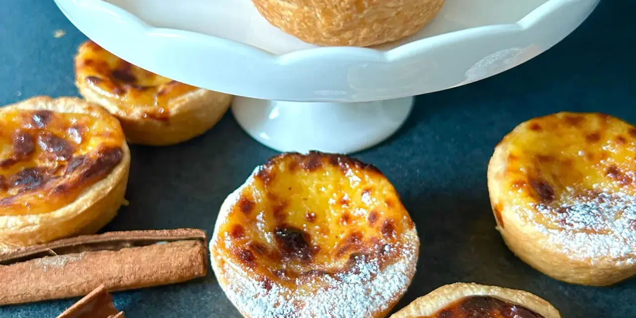 Fluffiga, gyllene pastel de nata med pudersocker och kanelstänger. En härlig fika!