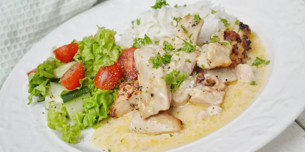 En krämig kycklinggryta med bacon, serverad med ris och en fräsch sallad.