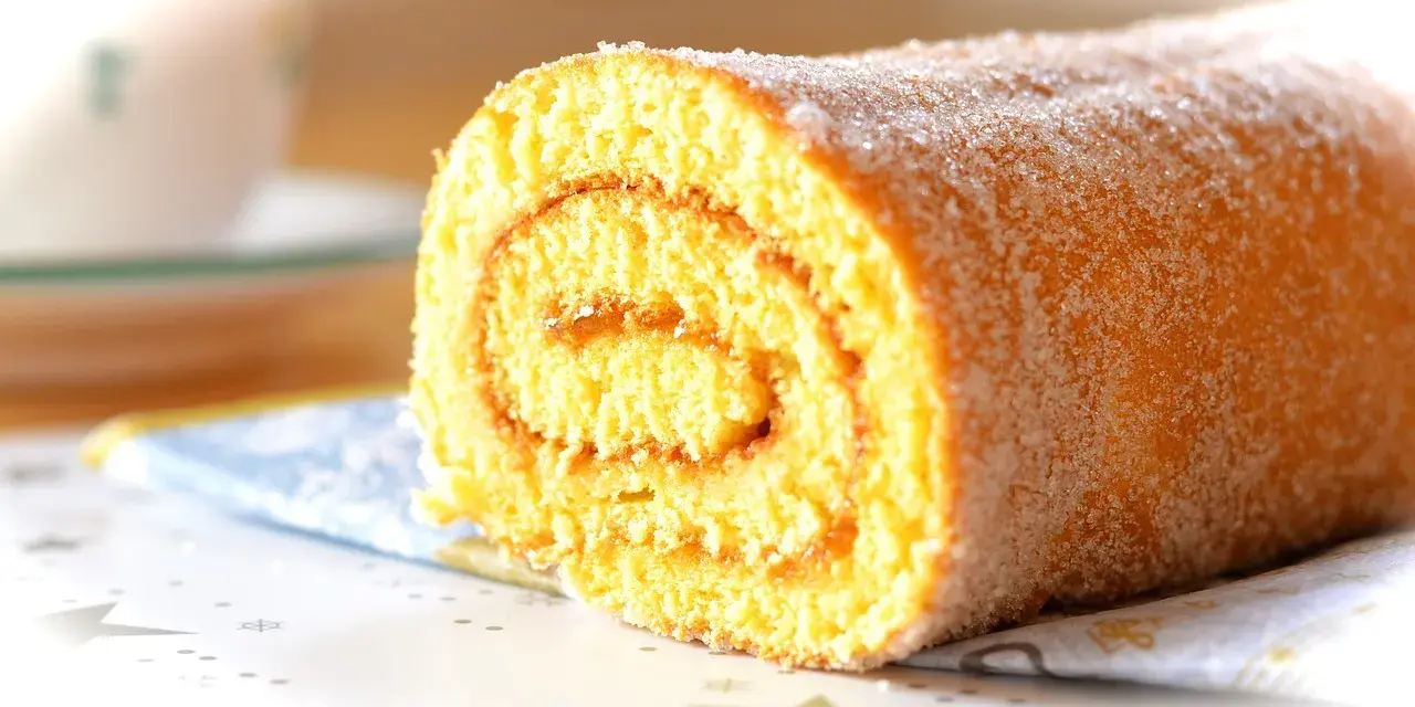 En sockerströdd rulltårta med marmeladfyllning, perfekt för ett enkelt rulltårta recept.