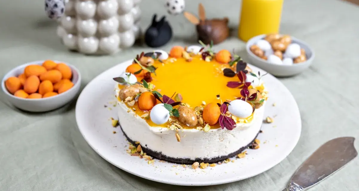 En vacker cheesecake med gul topping, dekorerad med påskägg och nötter. Perfekt för en härlig cheesecake påsk-firande.