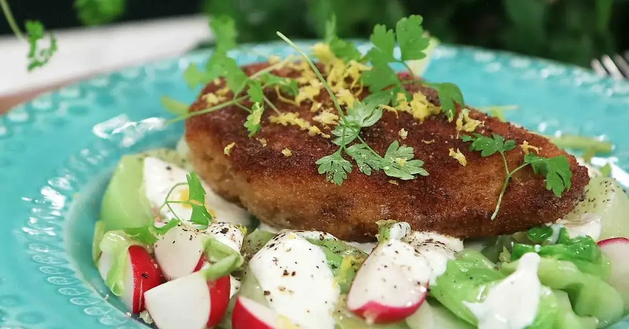 En gyllene kyckling kiev toppas med citronzest och persilja, serverad på en bädd av krispig sallad med rädisor och krämig dressing.