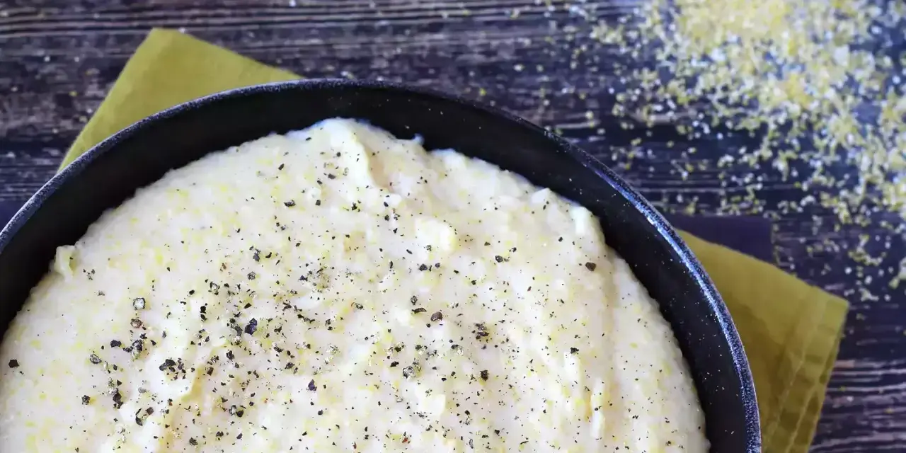Krämig polenta i en gjutjärnspanna, strödd med peppar. Perfekt för ett enkelt polenta recept.