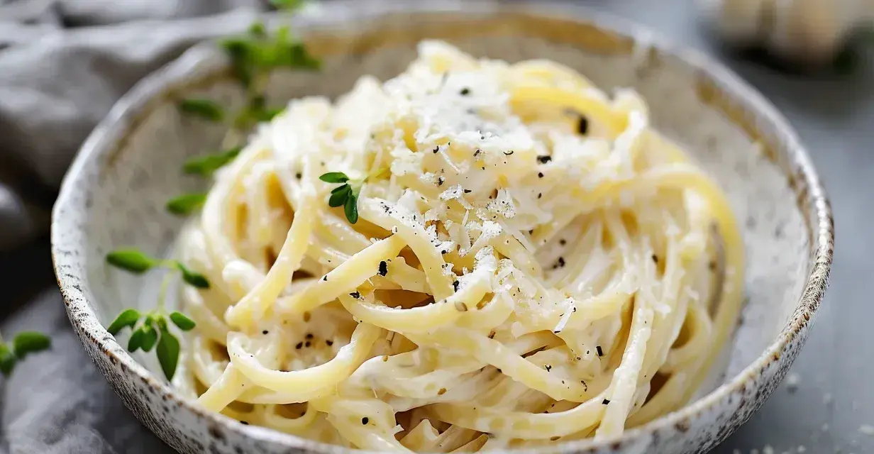 En skål med krämig ostsås pasta, toppad med riven ost och färska örter. En perfekt middag!