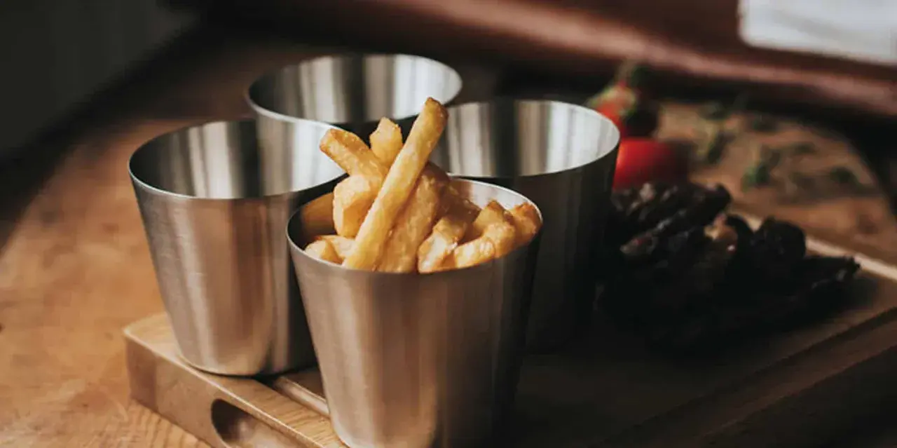 Friterade pommes i kastrull, serverade i små metallmuggar. En läcker aptitretare som påminner om hemgjord snabbmat.