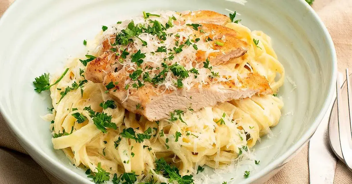 En krämig portion chicken alfredo med tagliatelle, toppad med grillad kyckling, parmesan och färsk persilja.