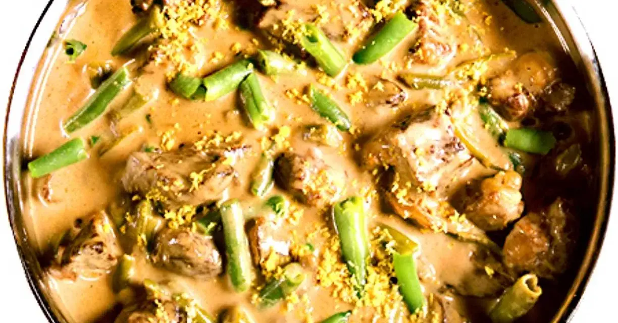 En krämig biff stroganoff med möra köttbitar och gröna bönor, toppad med gul strössel.
