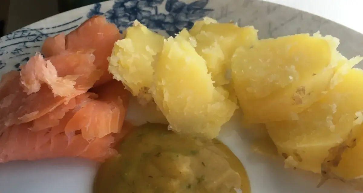 En tallrik med gravad lax, kokt potatis och en klick gravlaxsås. Perfekt för ett snabbt och gott recept.
