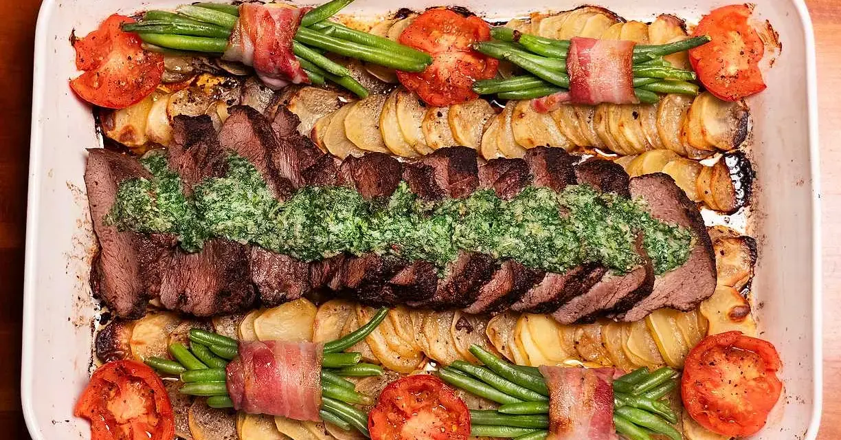 En saftig coeur de filet provencale med potatis, gröna bönor inslagna i bacon och tomater i en ugnsform.