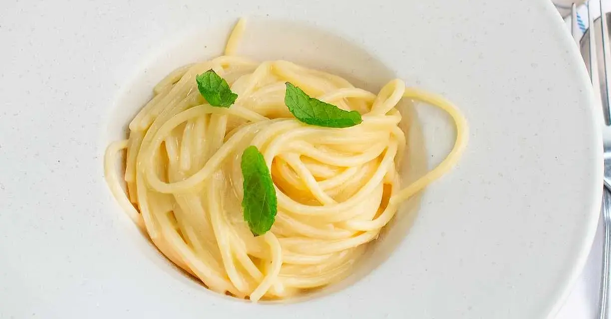 En krämig pasta limone, serverad i en vit skål med färska myntablad.