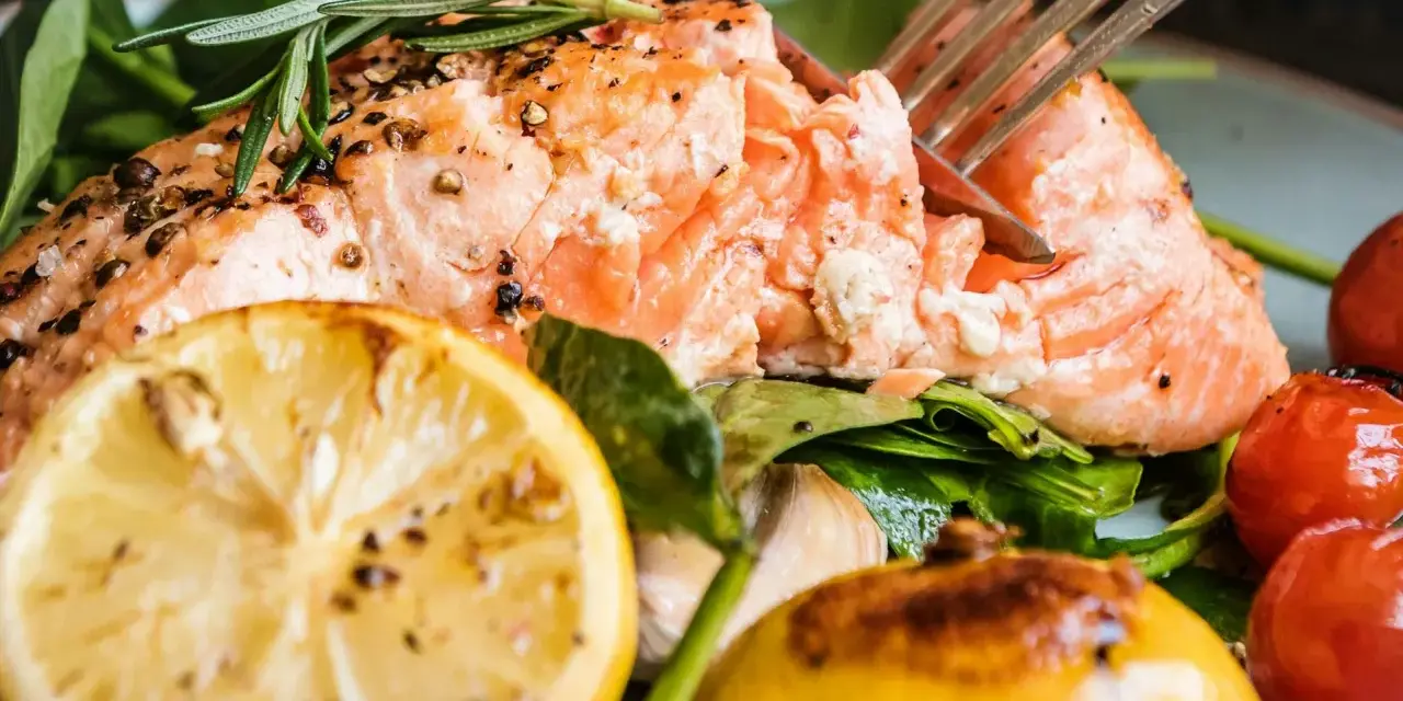 En saftig bit inkokt lax i ugn, serverad med citron, körsbärstomater och färska örter. En härlig måltid!