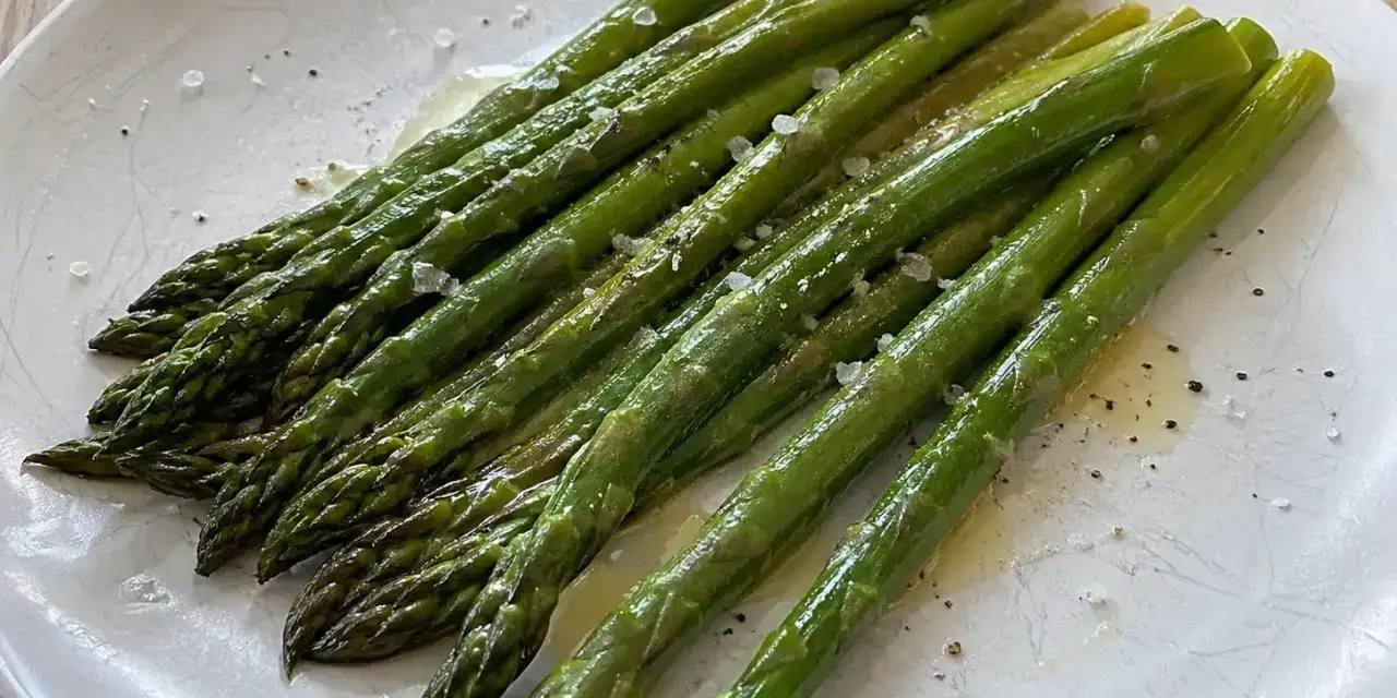 En tallrik med nykokt sparris, lätt oljad och strödd med flingsalt och peppar. Perfekt för att koka sparris till en enkel och god rätt.