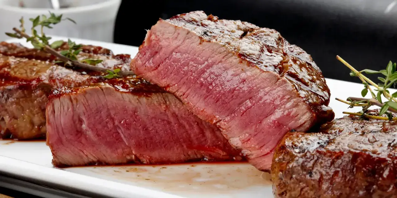 Perfekt grillad oxfilé med saftig rosa kärna, serverad med en glansig glaze och färsk timjan.