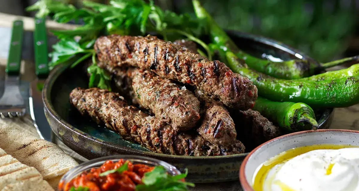 Grillade cevapcici med gröna paprikor, persilja, pitabröd och en röd röra. Ett perfekt cevapcici recept för sommaren.