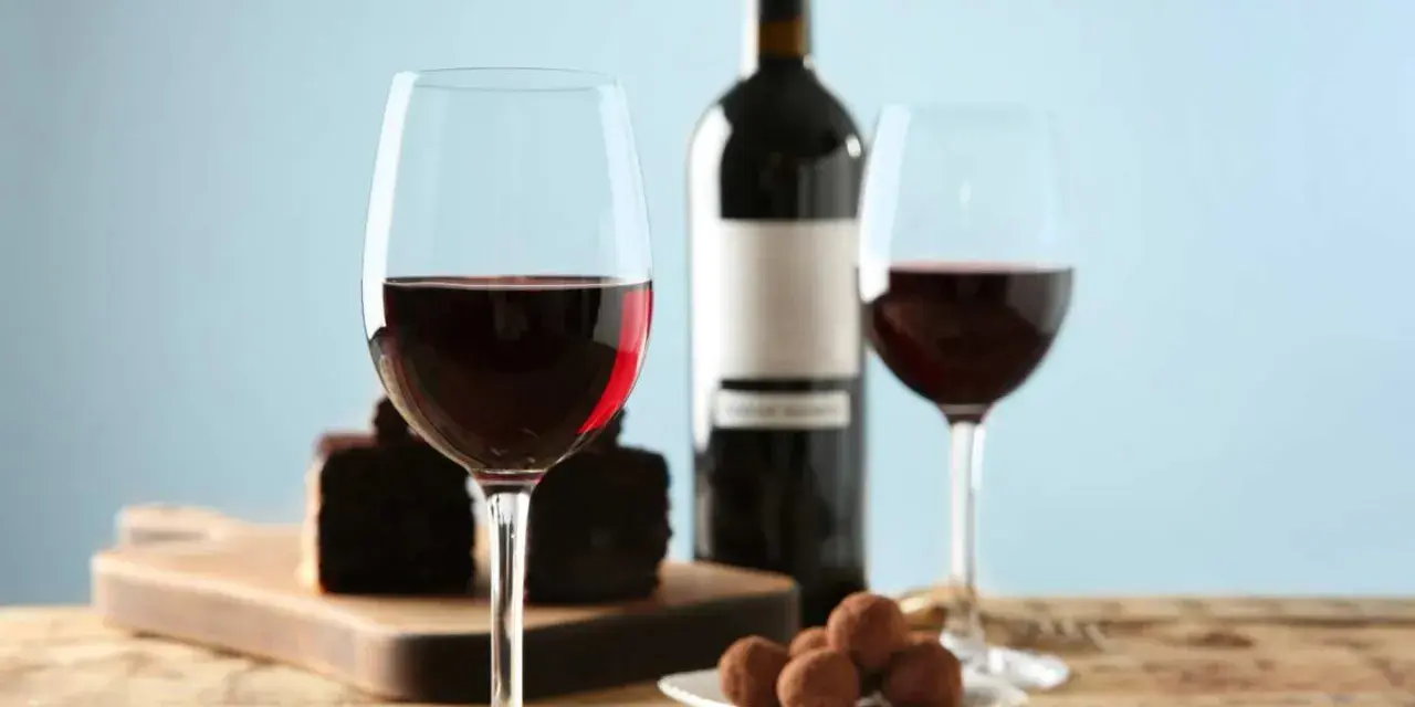 Två glas rött vin, en flaska, chokladpraliner och en bit chokladkaka. En perfekt kombination av vin till choklad.