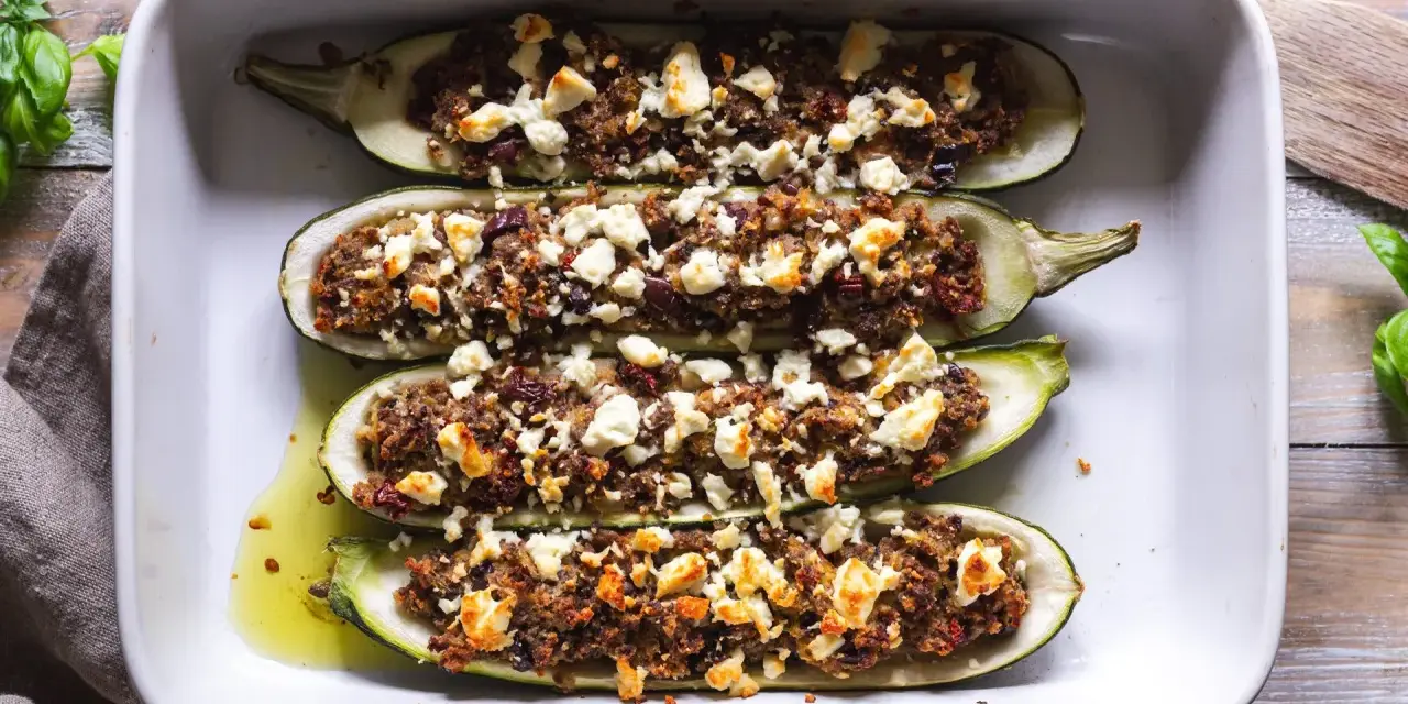 Ugnsbakade zucchinihalvor fyllda med en smakrik blandning och toppade med smulad fetaost. En härlig rätt med zucchini i ugn med fetaost.