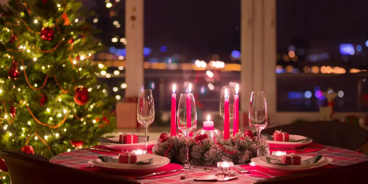 Ett dukat bord med julgran och tända ljus, redo för ett härligt vin till julbordet.