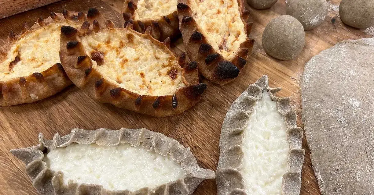 Färdiga piroger och ingredienser för piroger recept. Degbollar, kavlad deg och nybakade piroger med ostfyllning.
