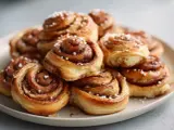 En hög med gyllene, nybakade glutenfria kanelbullar, toppade med pärlsocker. Perfekt för fikat!
