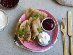 En tallrik med glutenfria pannkakor, serverade med sylt och grädde. En härlig frukost eller fika!