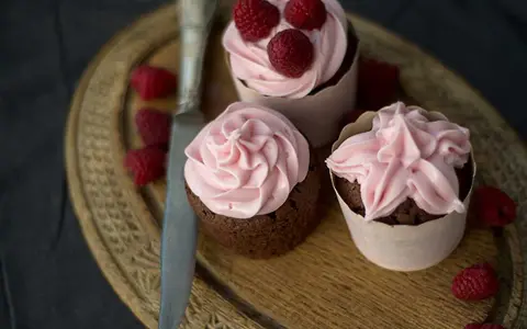 Tre chokladcupcakes med rosa frosting och hallon, redo att avnjutas. Ett perfekt cupcakes recept för alla tillfällen.