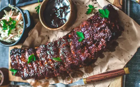 Saftiga spareribs i ugn, glaserade och serverade med en skål coleslaw och BBQ-sås. Perfekt för en festmåltid!