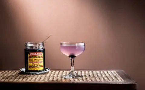 En elegant aviation drink med en burk Luxardo maraschino-körsbär, redo att förhöja smaken.