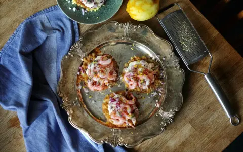 Tre potatisbullar med räkor, rödlök och dill på en silverbricka. Ett recept på potatisbullar som ser utsökt ut!