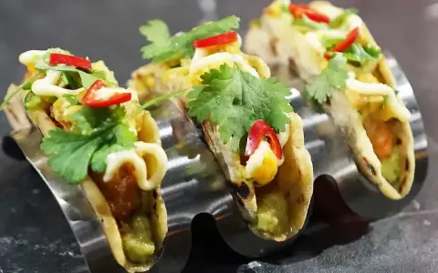 Tre läckra asiatiska tacos med koriander, chili och majs i en taco-hållare.