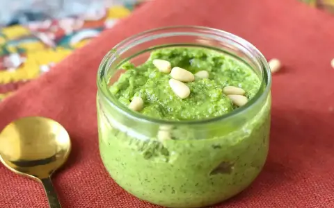 En burk med hemgjord pesto, toppad med pinjenötter. Perfekt för ditt nästa pesto recept!