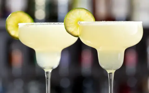 Två frostiga frozen margaritas med saltkant och lime, redo att avnjutas.
