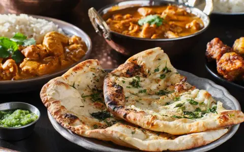 En härlig måltid med indisk mat, inklusive naanbröd, kycklingcurry och ris. Perfekt för en kväll med vin till indisk mat.