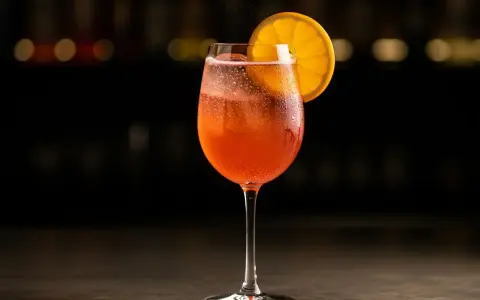 Ett glas med bubblig, orange drink, troligen en cava aperol, med en apelsinskiva som garnering.