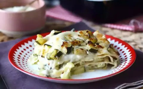 En bit krämig vegetarisk lasagne med zucchini, toppad med gyllene ost och grönsaker.