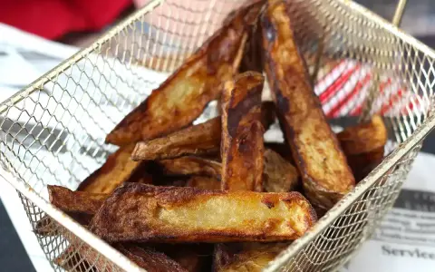 Krispiga pommes frites i airfryer, gyllene och redo att serveras i en metallkorg.