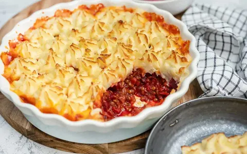En gyllene shepherd's pie med potatismoslock, fylld med en mustig lins- och rotfruktsröra. Serveras med rödbetor.