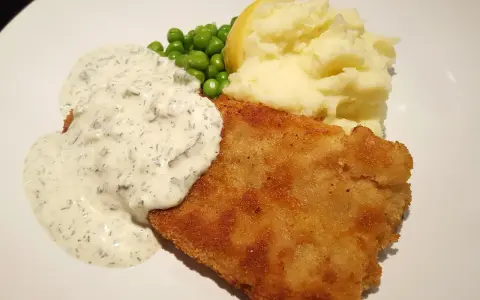 En gyllene panerad fisk med krämig sås, ärtor och potatismos. En klassisk och god måltid.
