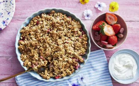 En härlig gammaldags rabarberpaj med krispigt täcke, serverad med färska jordgubbar och grädde. Perfekt sommardessert!
