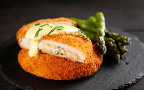 Krispig cordon bleu med krämig fyllning och hollandaisesås, serverad med sparris.