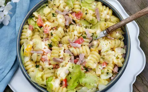 En krämig pastasallad med skinka, grönsaker och en dressing baserad på olja. Perfekt till sommaren!