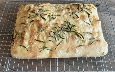 En gyllene, nybakad focaccia med rosmarin och flingsalt, perfekt för ditt nästa focaccia recept.