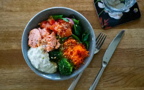En härlig poke bowl med lax, broccoli, tomat, rivna morötter och en krämig sås. Perfekt för en hälsosam lunch.