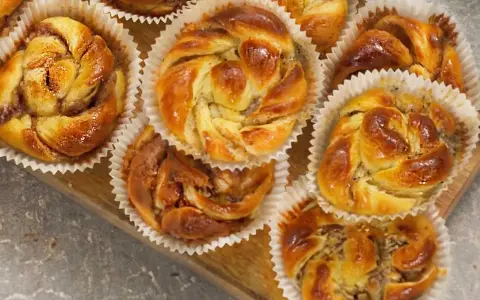 Nybakade bullar med mandelmassa och vallmofrön, gyllene och glansiga i sina pappersformar.