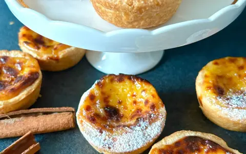 Fluffiga, gyllene pastel de nata med pudersocker och kanelstänger. En härlig fika!