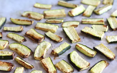 Skivor av zucchini i ugn, lätt gyllene och kryddade, redo att serveras.