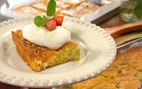 En saftig rabarberkaka i långpanna, toppad med fluffig grädde och färska myntablad. Perfekt för fika!