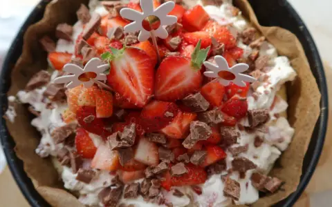 En läcker cheesecake med jordgubbar och chokladbitar, perfekt för ett somrigt cheesecake recept. Blomsterpinnar dekorerar toppen.