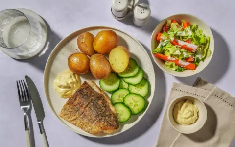 En tallrik med stekt vit fisk, kokt potatis, gurka och en klick majonnäs. Ett perfekt vit fisk recept för en snabb middag.