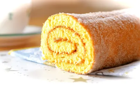 En sockerströdd rulltårta med marmeladfyllning, perfekt för ett enkelt rulltårta recept.