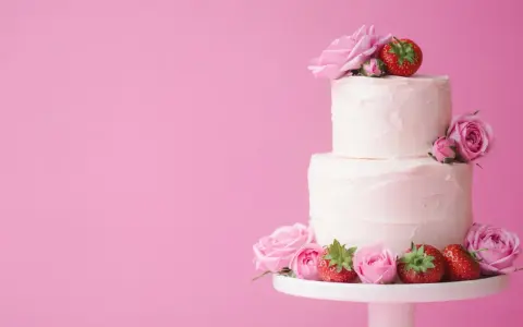 En vacker tvåvåningstårta med rosa frosting, dekorerad med rosor och jordgubbar. Perfekt för ett sommarbröllop eller en fest. Ett enkelt tårta recept att följa.